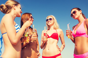 Image showing group of smiling young women drinking on beach