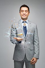 Image showing happy businessman in suit showing virtual screens