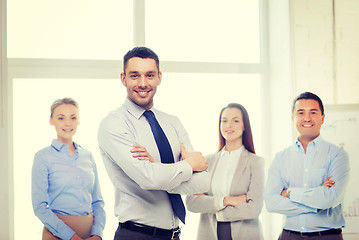 Image showing smiling businessman in office with team on back