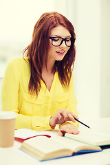 Image showing smiling student girl reading books in library