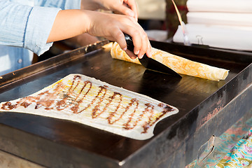 Image showing close up of cook frying pancakes at street market