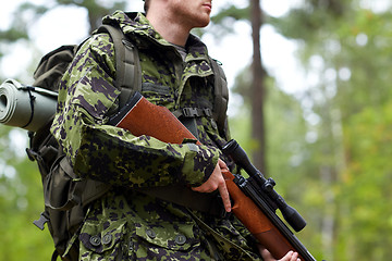 Image showing close up of soldier or hunter with gun in forest