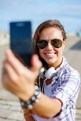 Image showing smiling teenager taking picture with smartphone