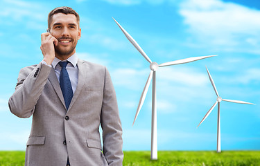 Image showing smiling businessman with smartphone outdoors