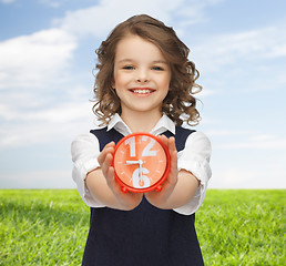 Image showing happy girl with alarm clock over summer background