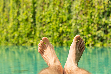 Image showing close up of male feet over resort swimming pool