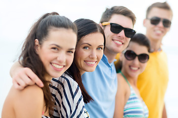 Image showing group of happy friends hugging on beach