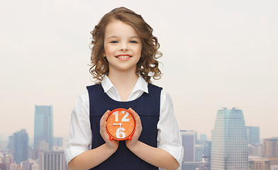 Image showing happy girl with alarm clock over city background