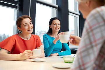 Image showing happy young women drinking tea or coffee at cafe