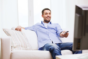 Image showing smiling man with tv remote control at home