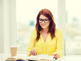 Image showing smiling student girl reading books in library