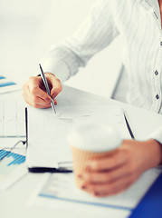 Image showing woman filling in blank paper and drinking coffee