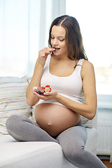 Image showing happy pregnant woman eating fruits at home