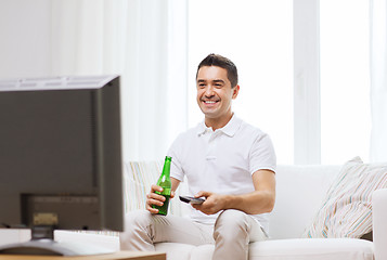 Image showing smiling man watching tv and drinking beer at home