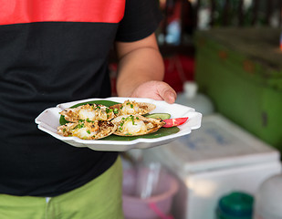 Image showing close up of hand holding seafood at street market