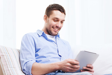 Image showing smiling man with tablet pc and cup at home