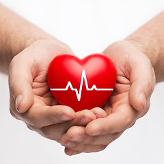 Image showing male hands holding heart with ecg line