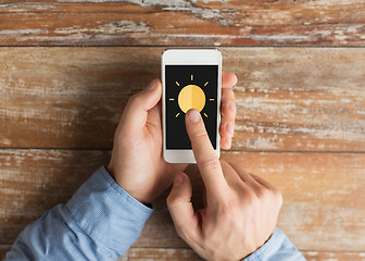 Image showing close up of hands with sun icon on smartphone