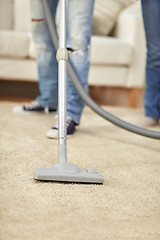 Image showing close up of human legs and vacuum cleaner at home