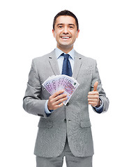 Image showing smiling businessman with money showing thumbs up