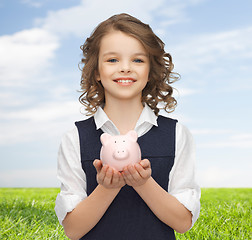 Image showing happy girl holding piggy bank on palms
