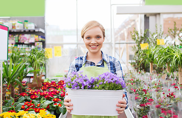 Image showing happy woman holding flowers in greenhouse