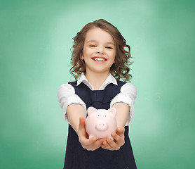 Image showing happy girl holding piggy bank on palms