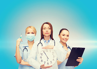 Image showing calm female doctor and nurses with wall clock