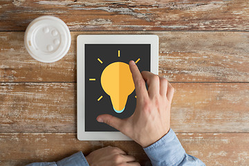 Image showing close up of hands with ligting bulb on tablet pc