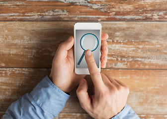 Image showing close up of hands with magnifier on smartphone