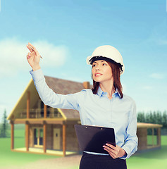 Image showing smiling businesswoman in helmet with clipboard