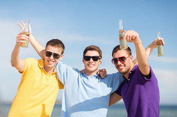 Image showing happy friends with beer bottles on beach