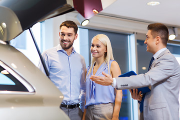 Image showing happy couple with car dealer in auto show or salon