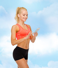 Image showing smiling sporty woman with smartphone and earphones