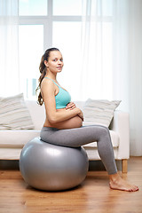 Image showing happy pregnant woman exercising on fitball at home