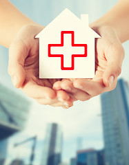 Image showing hands holding paper house with red cross