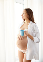 Image showing happy pregnant woman with cup drinking tea at home