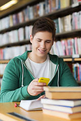 Image showing male student with smartphone texting in library