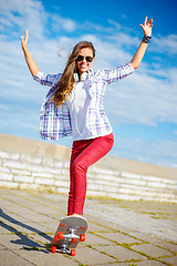 Image showing smiling teenage girl riding skate outside