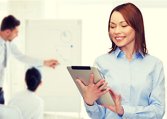 Image showing smiling woman looking at tablet pc at office