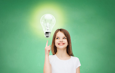 Image showing smiling school girl pointing finger to light bulb