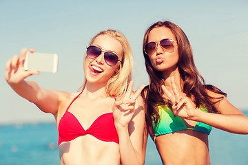 Image showing two smiling women making selfie on beach