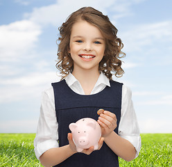 Image showing happy girl holding piggy bank and coin