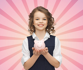 Image showing happy girl holding piggy bank on palms