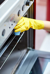 Image showing close up of woman cleaning oven at home kitchen