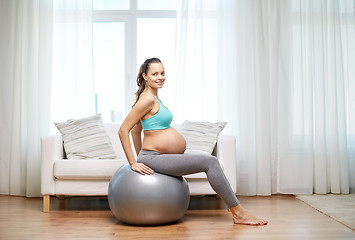 Image showing happy pregnant woman exercising on fitball at home