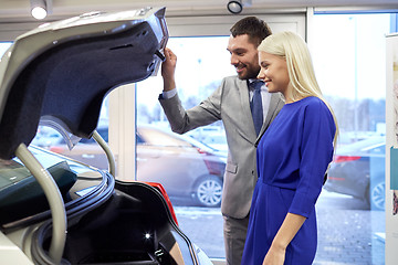 Image showing happy couple with car dealer in auto show or salon