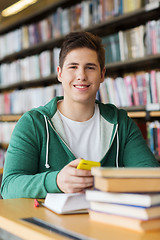 Image showing male student with smartphone and books in library