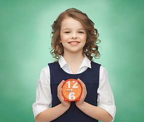 Image showing happy girl with alarm clock over green background 