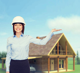 Image showing businesswoman in helmet holding something on palm